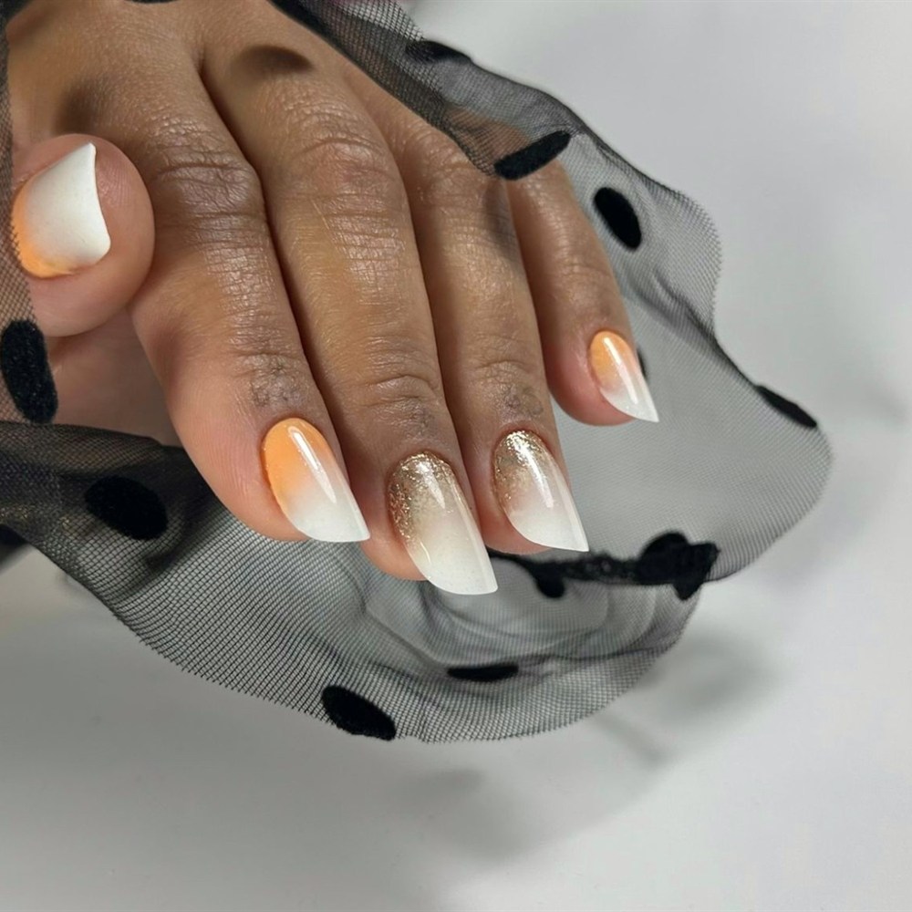 Uñas con degradado de naranja a blanco y purpurina dorada